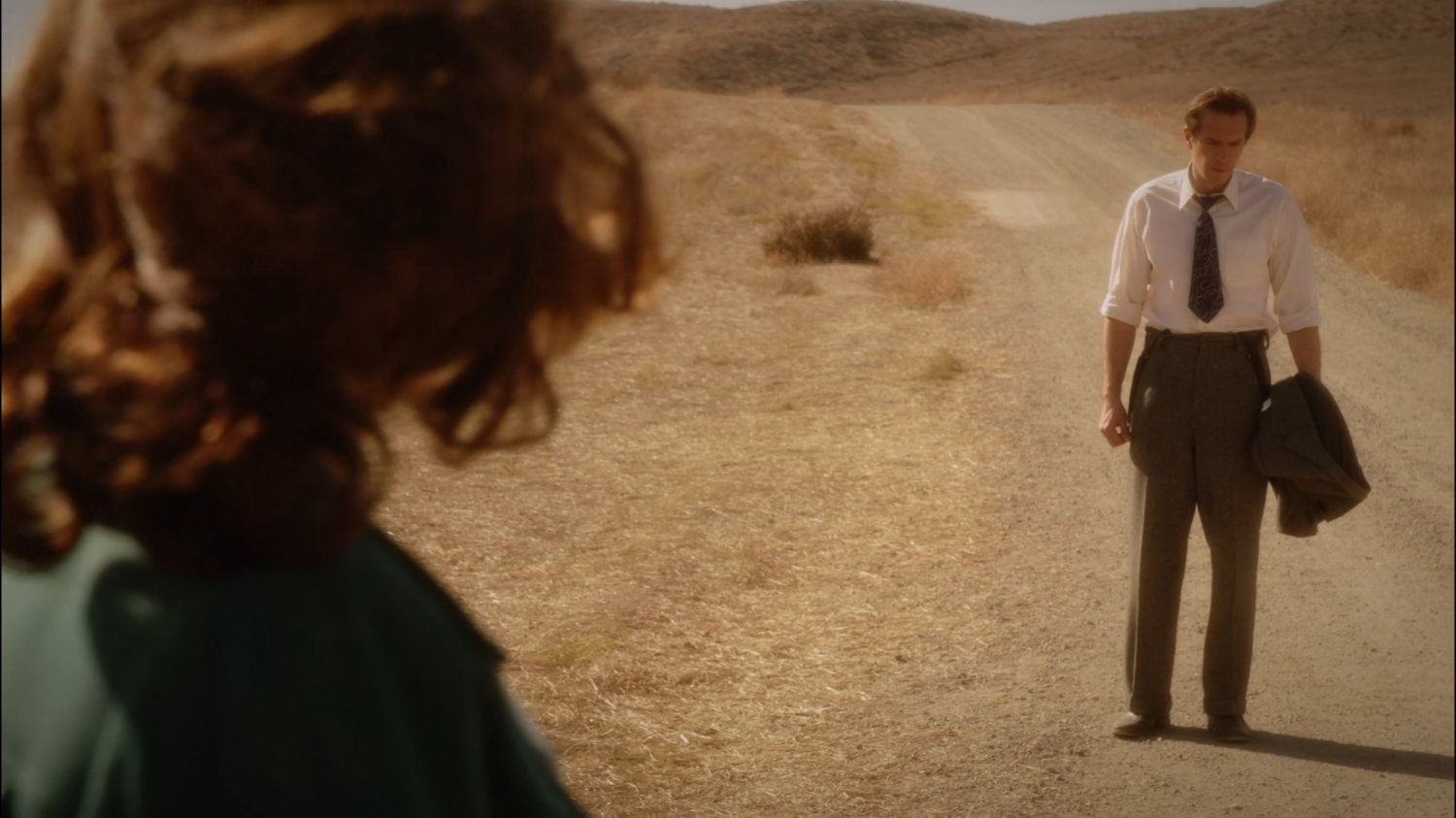 Peggy and Jarvis walking along dusty road in Mojave desert.