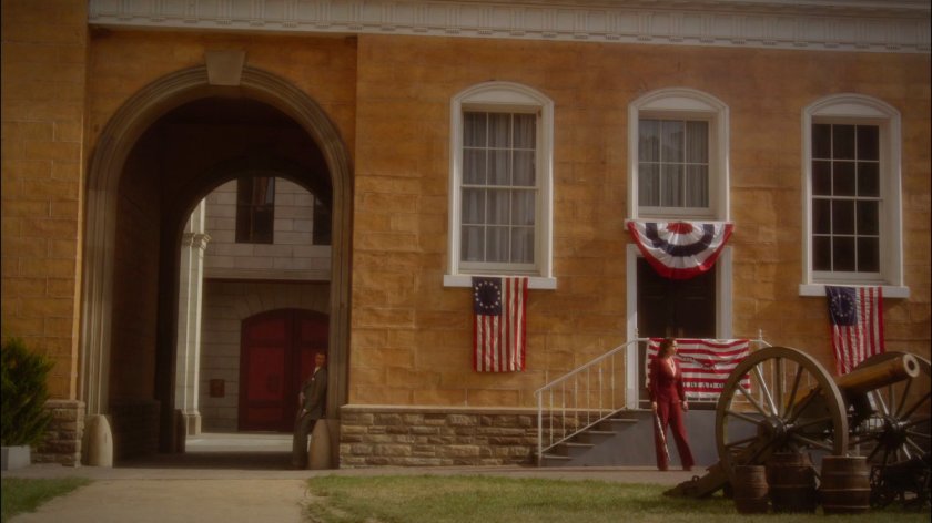Peggy and Thompson wait in town square on Stark Pictures backlot.