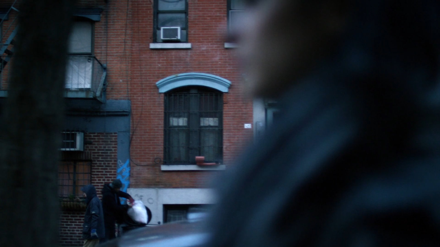 Jessica walking along a sidewalk, a building visible behind her.