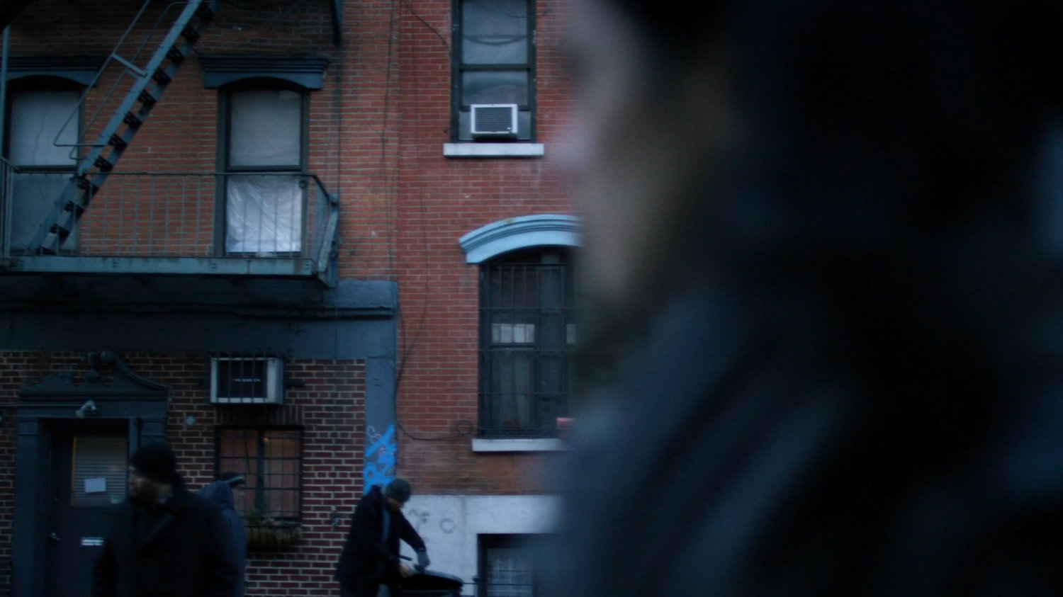 Jessica walking along a sidewalk, a building visible behind her.