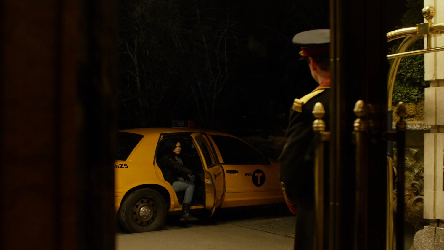 A doorman watches Jessica getting out of a taxi.