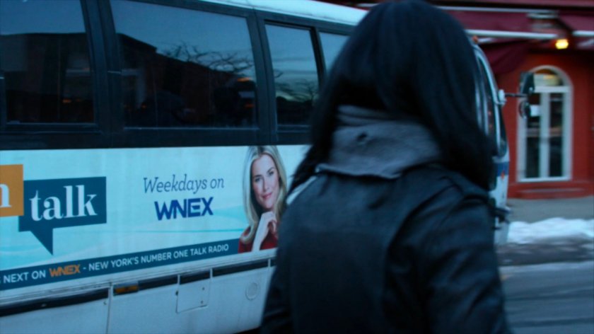 Jessica's watching bus turning corner with TrishTalk advert.