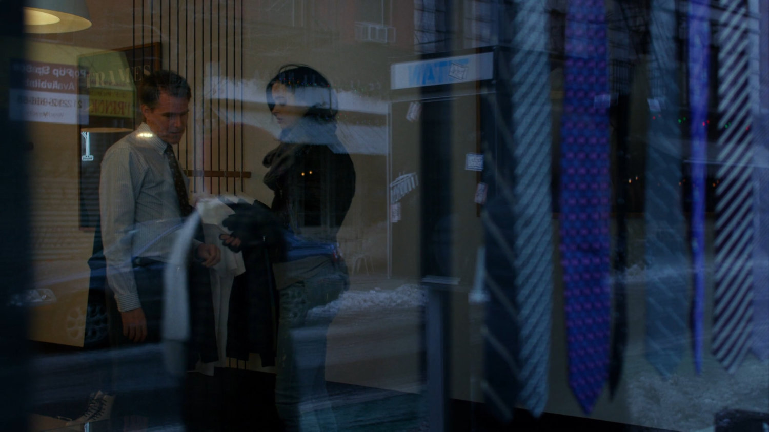 Jessica talking to man inside of tie shop.