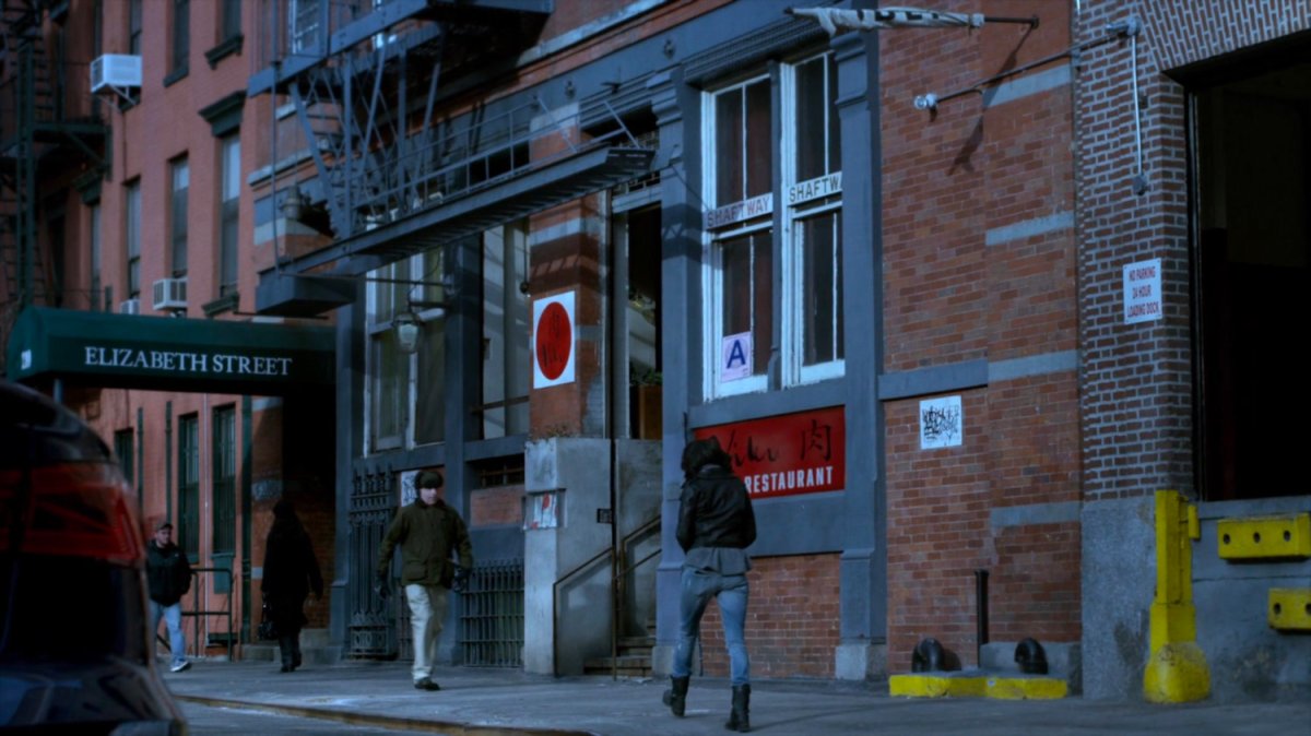 Jessica walking on sidewalk outside Niku Japanese restaurant.