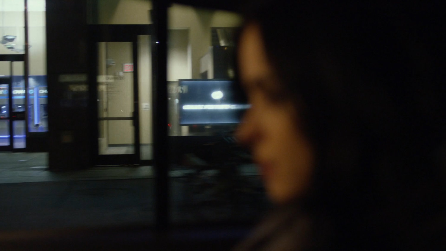 View of storefronts from taxi at night.