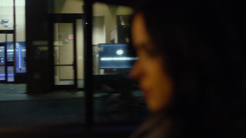 View of storefronts from taxi at night.