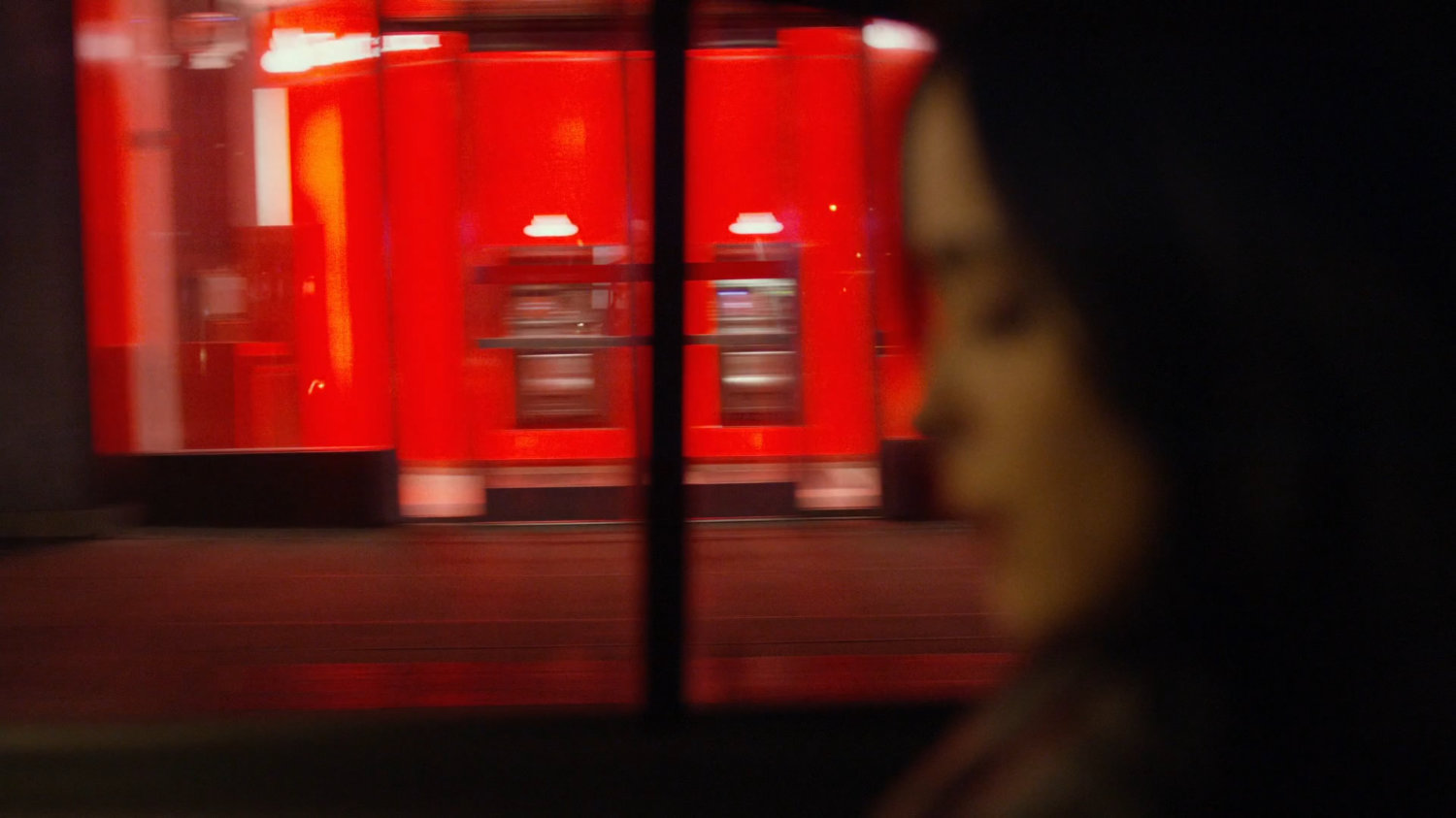 View of storefronts from taxi at night.