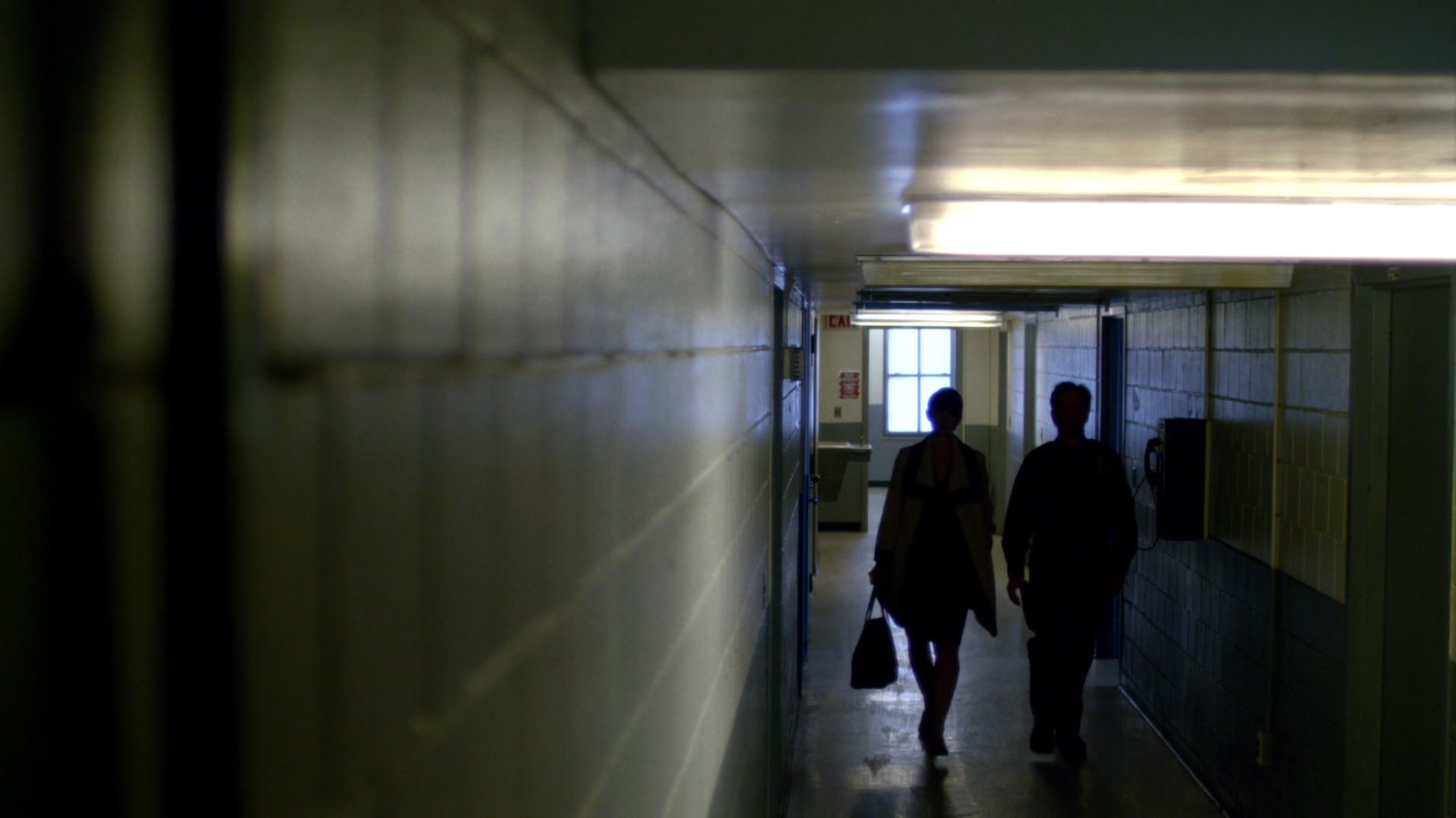 Jeri Hogarth and guard in correctional facility hallway.