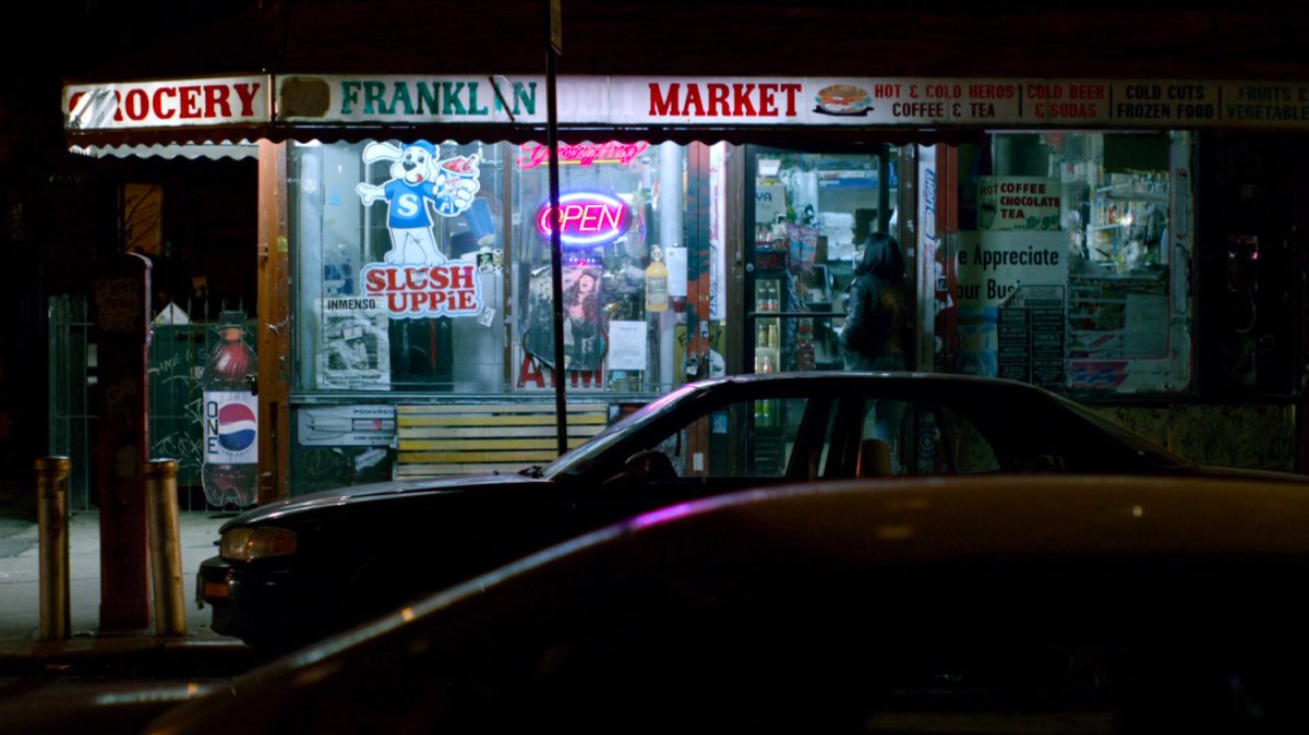 Jessica entering corner store at night.