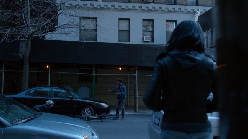 Jessica watching cyclist and Malcolm outside Alias Investigations building.