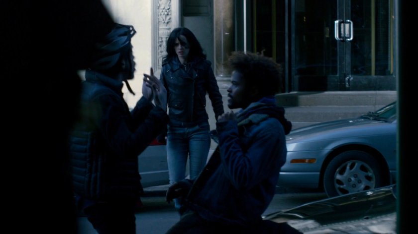 Jessica watching cyclist and Malcolm outside Alias Investigations building.