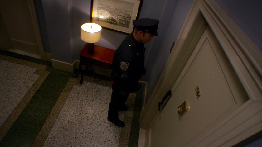 Officer Simpson outside Trish's apartment door.