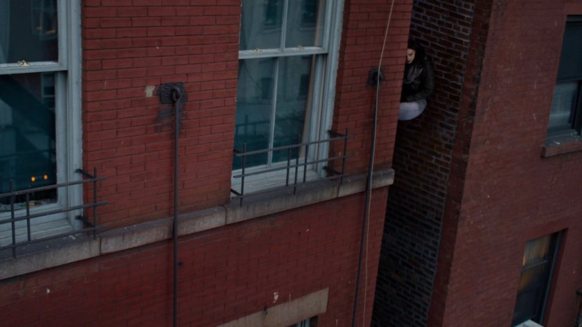 Jessica wedged between two building spying on Audrey Eastman.