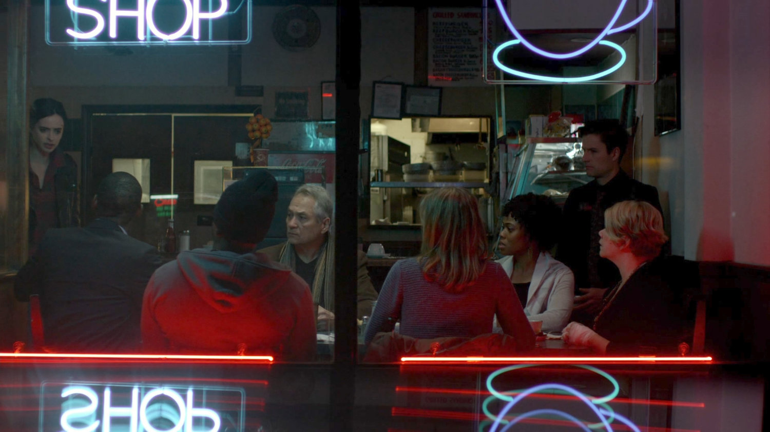 A support meeting of Kilgrave victims inside a diner.