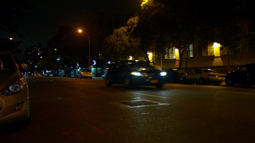 Car driving along a dark street at night.