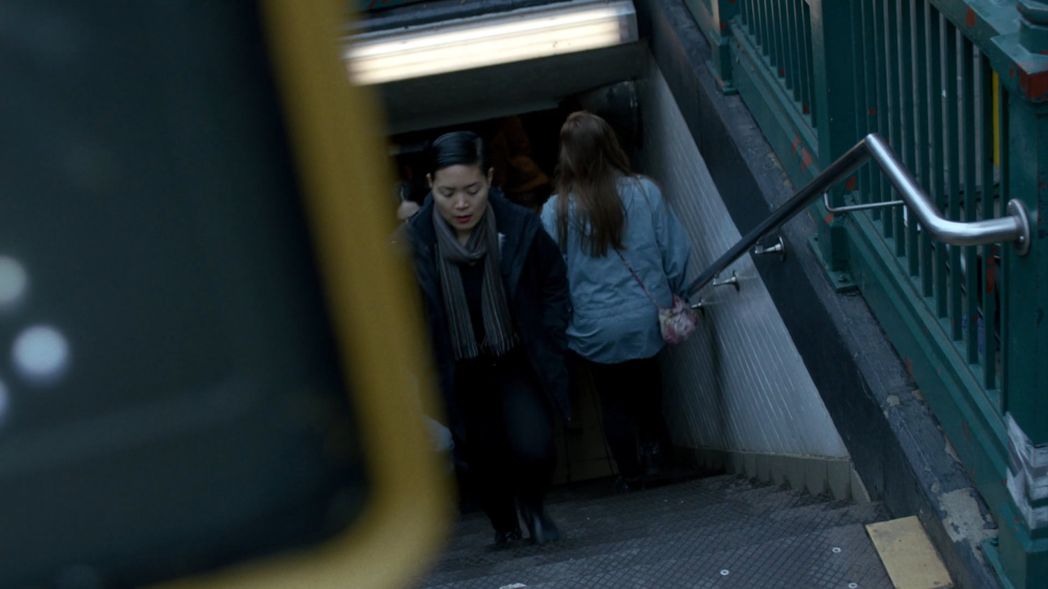 Pedestrians walking up stairs from a subway exit.
