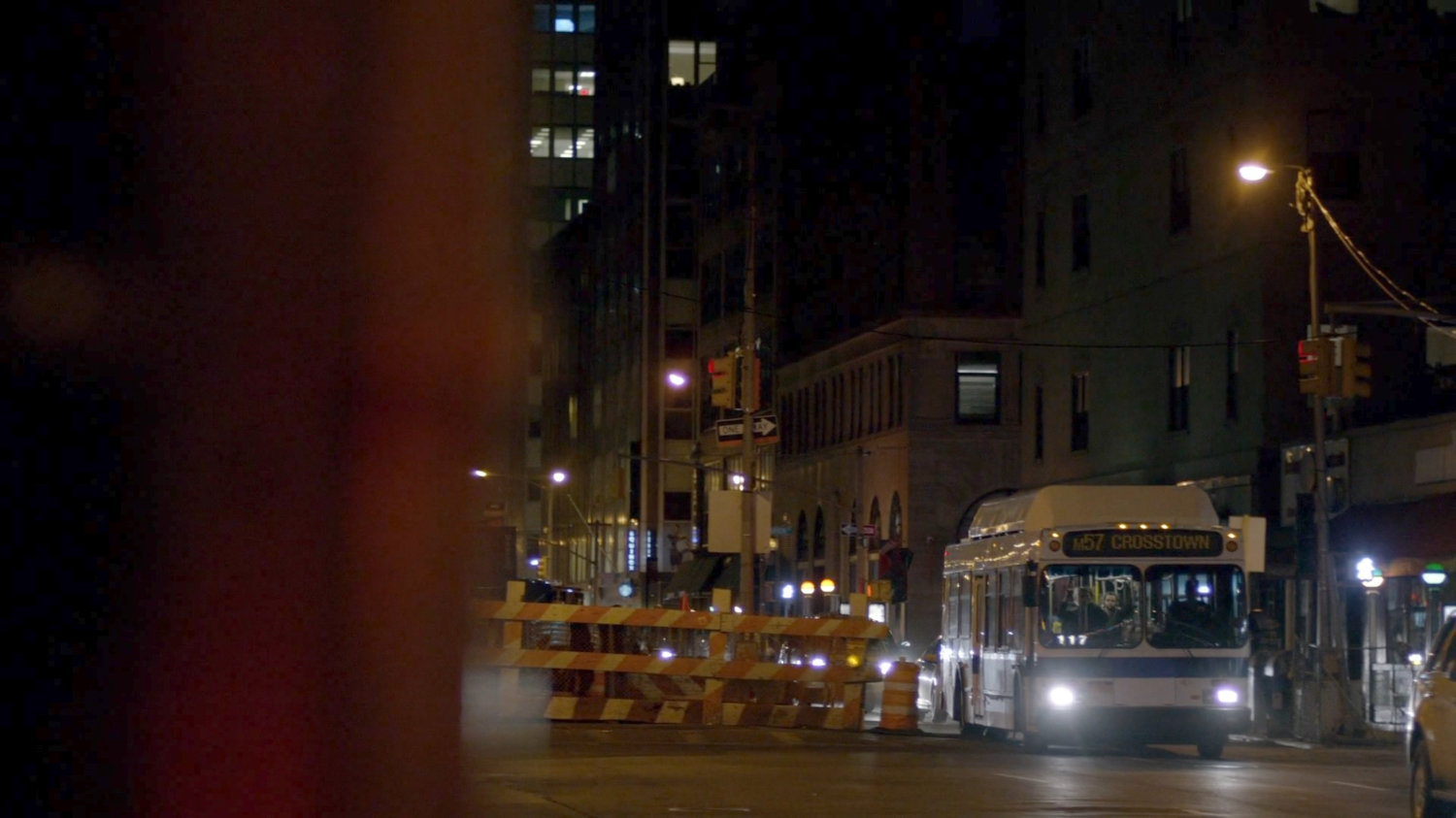 City bus driving along street at night.