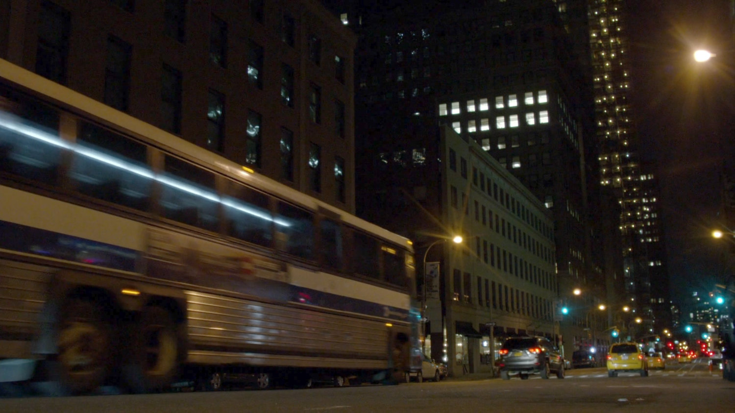 City bus driving along street at night.