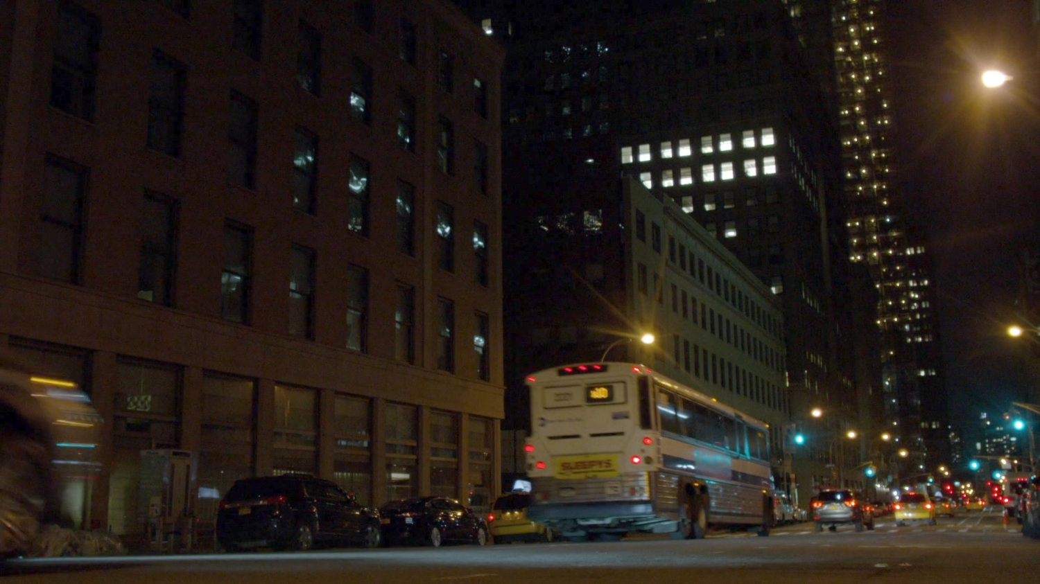 City bus driving along street at night.