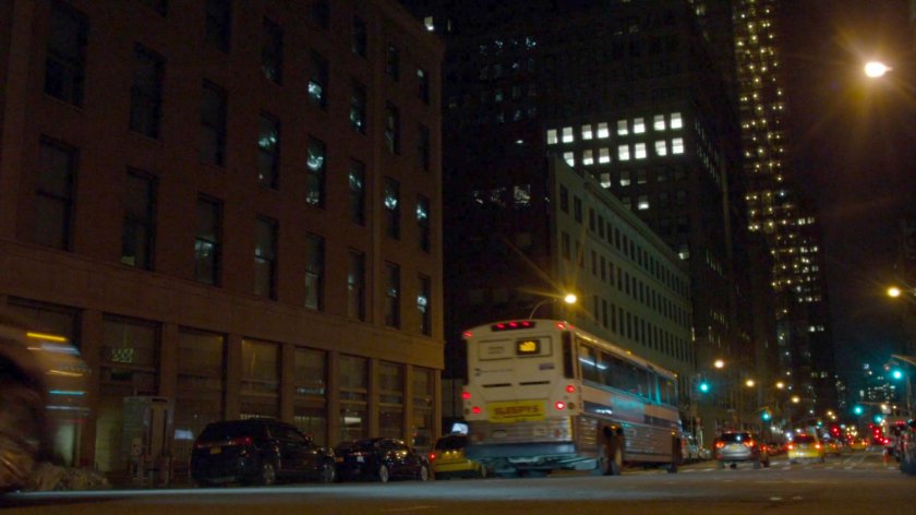 City bus driving along street at night.