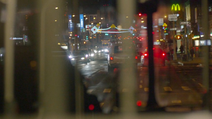 View from inside city bus on street at night.