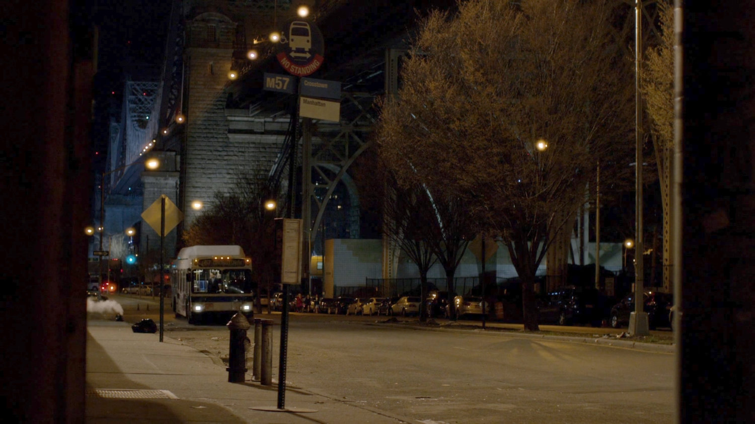 City bus pulling up to bus stop at night.