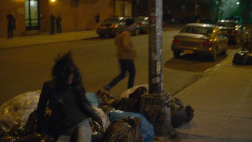 Jessica falling into a bundle of trash on sidewalk.