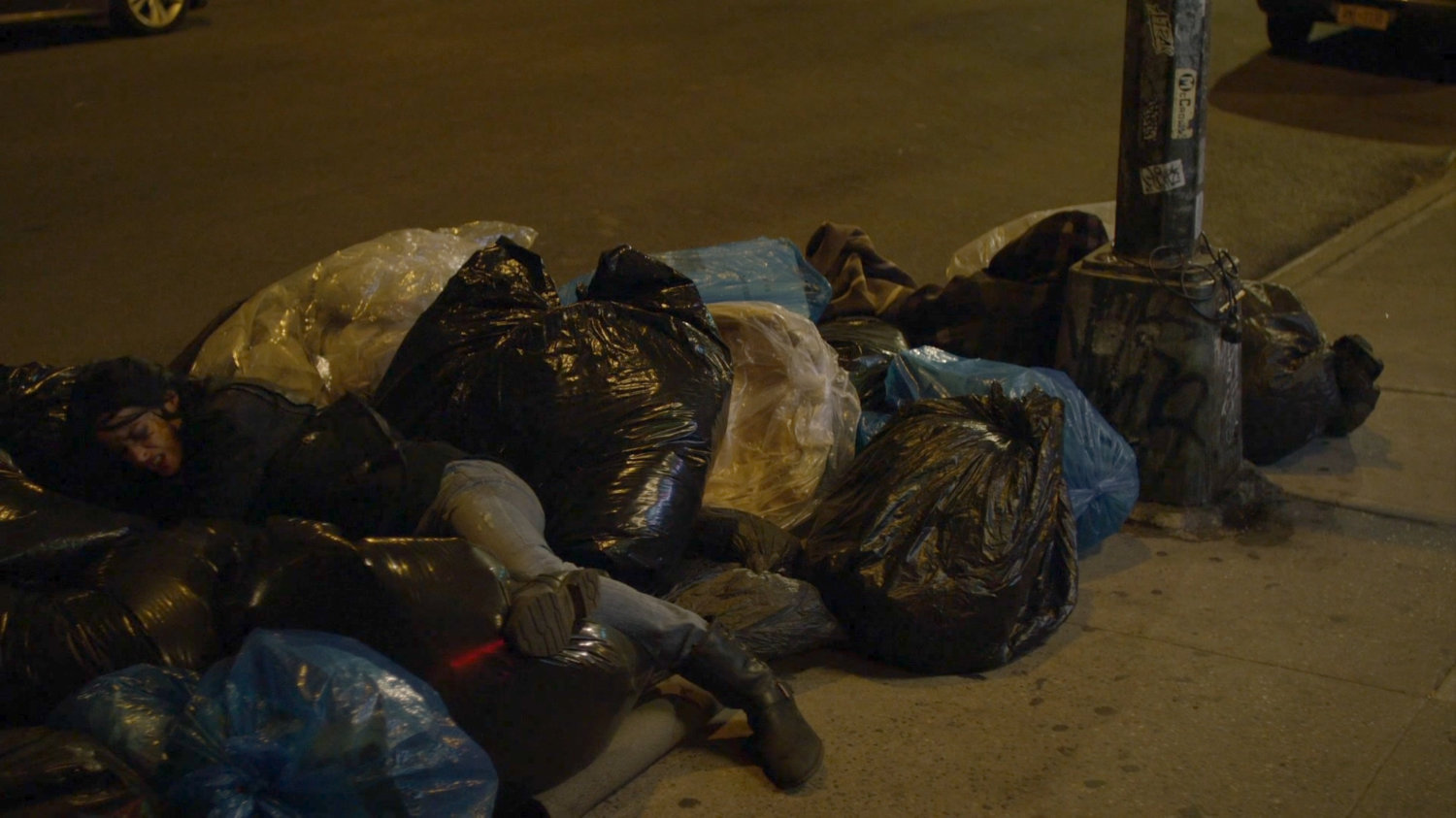 Jessica falling into a bundle of trash on sidewalk.