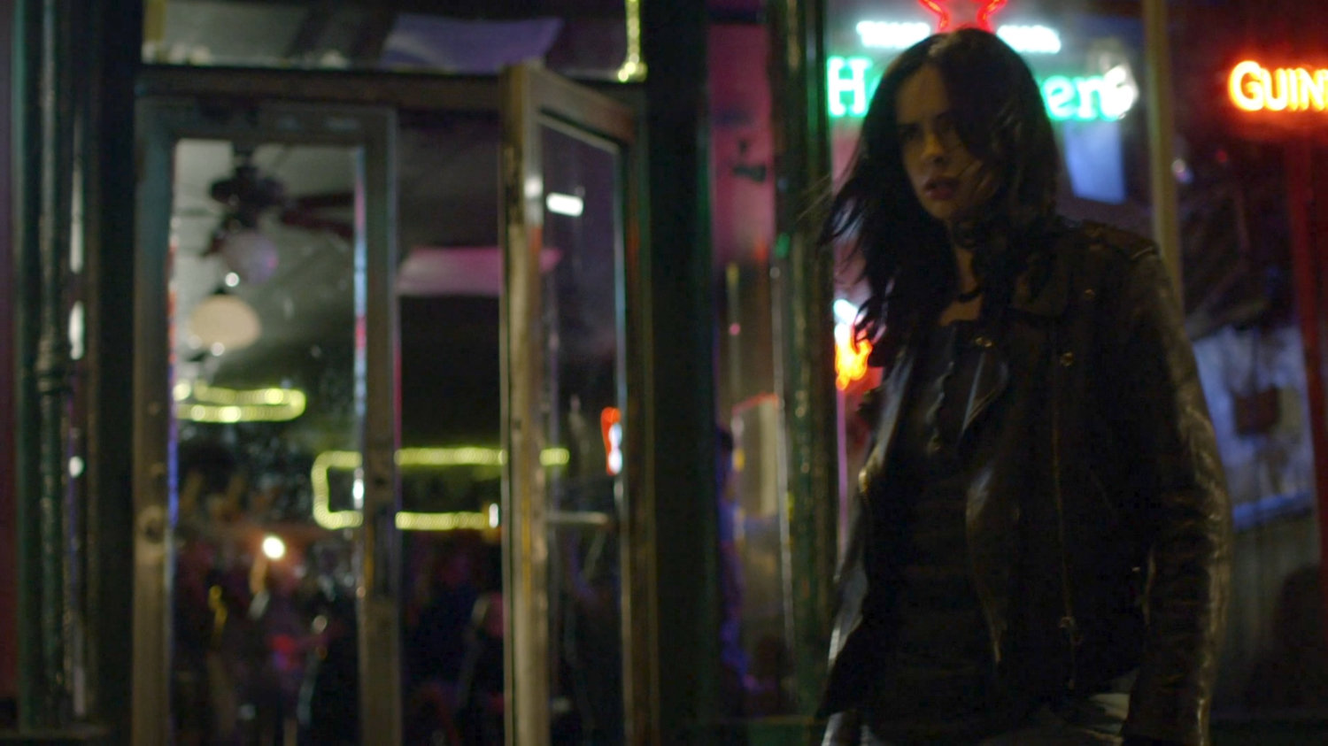 Jessica standing in front of bar at night.