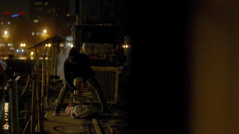 Malcolm hauling a body into a dock at night.