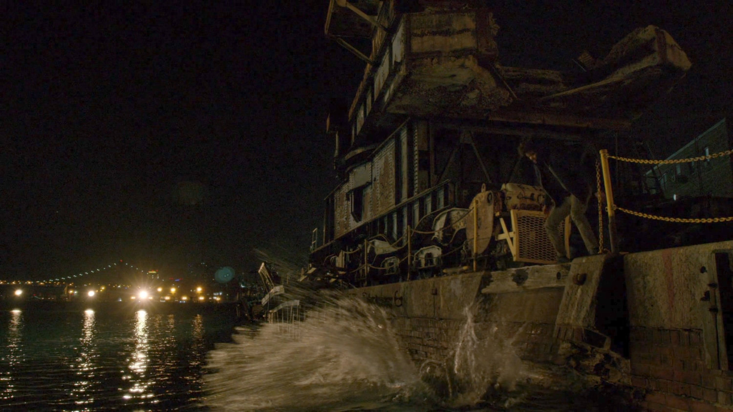 Malcolm dropping a body into the water at night.