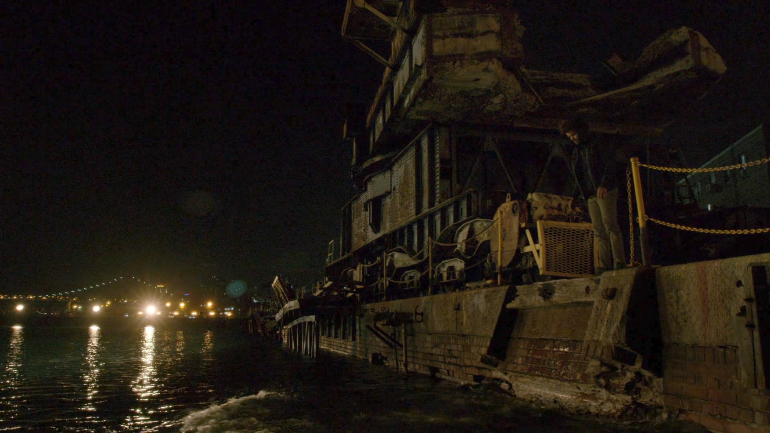 Malcolm dropping a body into the water at night.