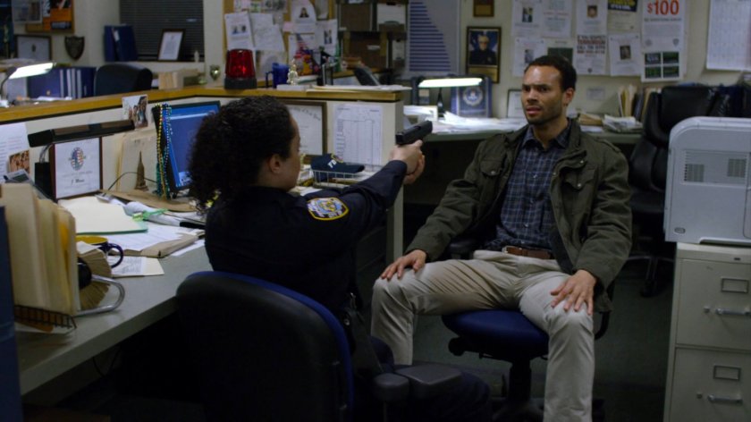 15th Precinct officer with gun drawn on another man. A Picture of Stan Lee is in the background.