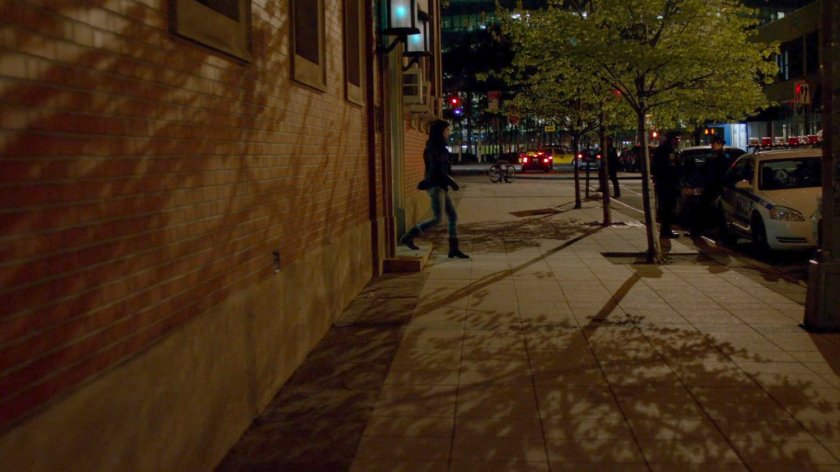 Jessica exits the 15th Precinct police station at night.