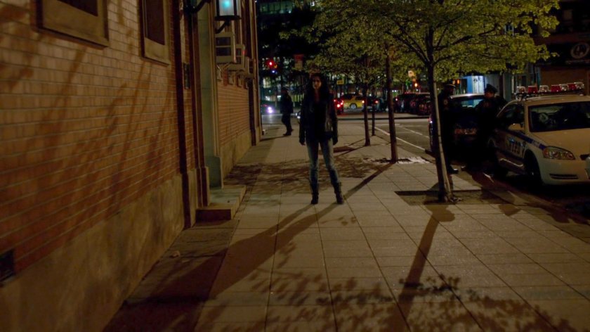 Jessica exits the 15th Precinct police station at night.