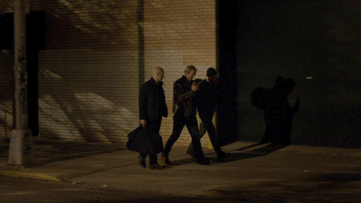 Simpson and two buddies walk along a sidewalk at night.