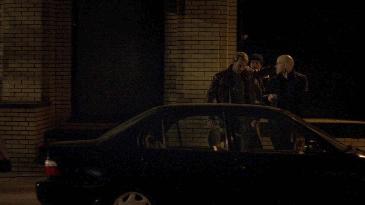 Simpson and two buddies walk along a sidewalk at night.