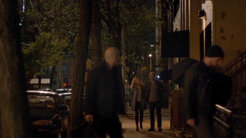 Simpson and Trish walk along a sidewalk at night.