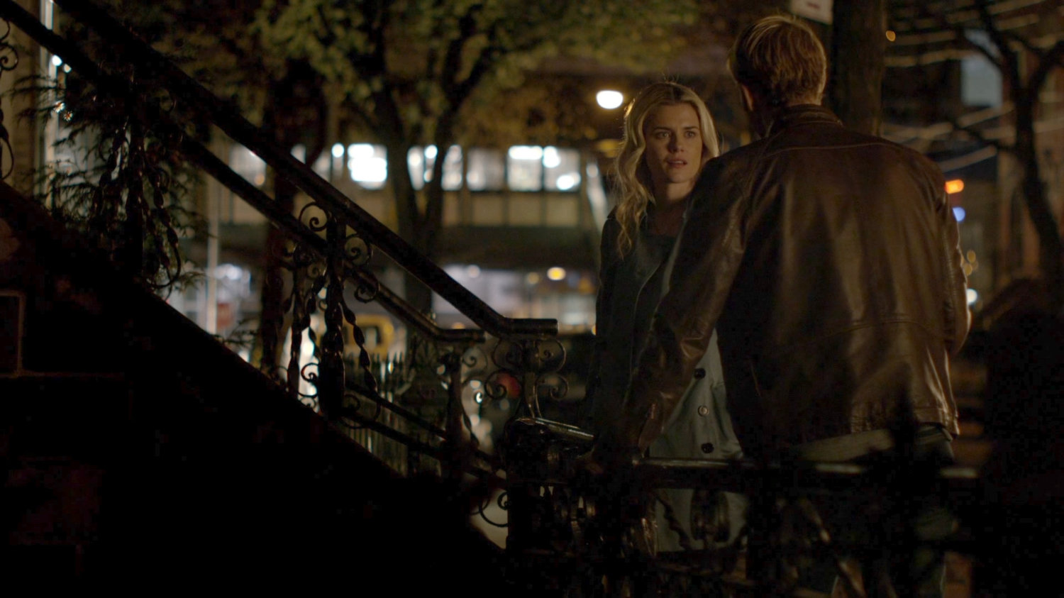 Simpson and Trish outside a brownstone at night.