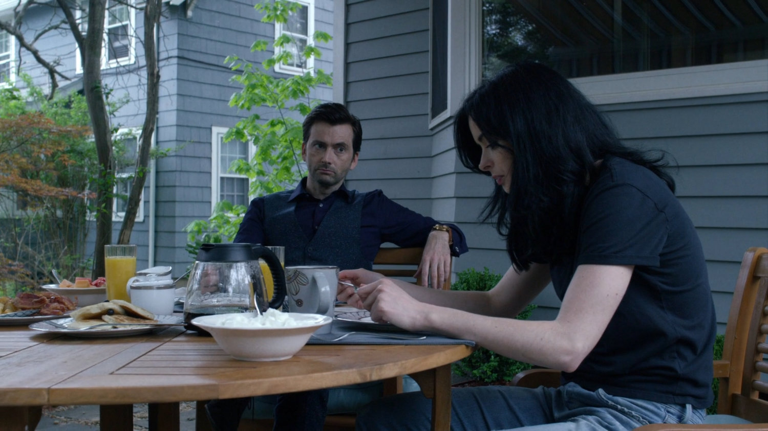 Kilgrave and Jessica at a table on back porch of her childhood home.