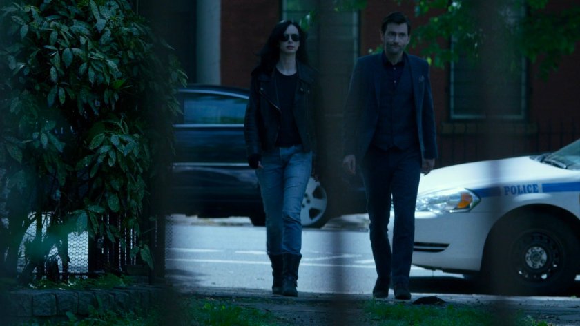 Jessica and Kilgrave walk through a backyard at a hostage situation.