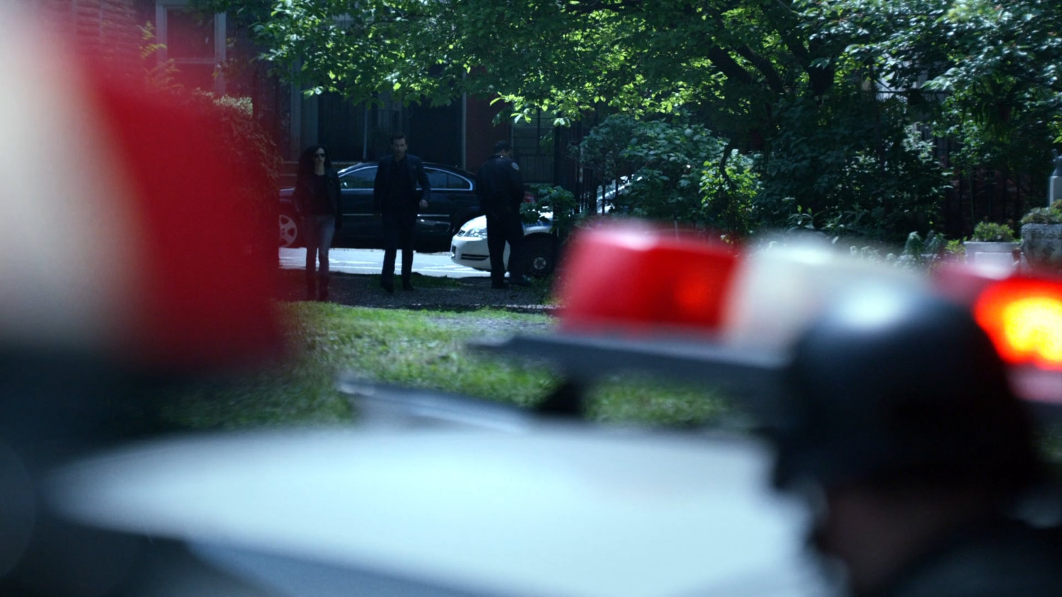 Jessica and Kilgrave walk through a backyard at a hostage situation.