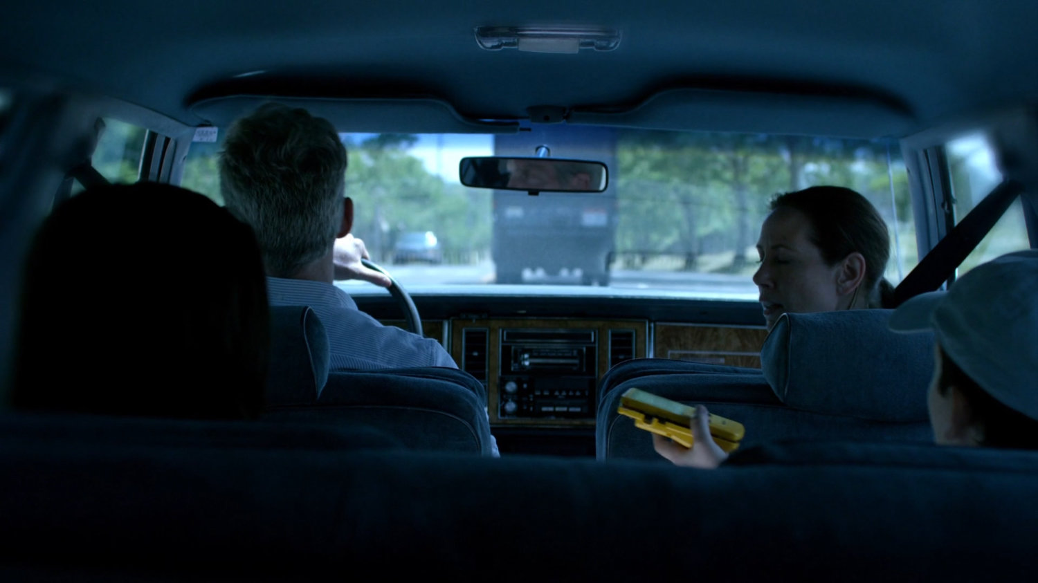 The Jones family in a car following behind a truck.