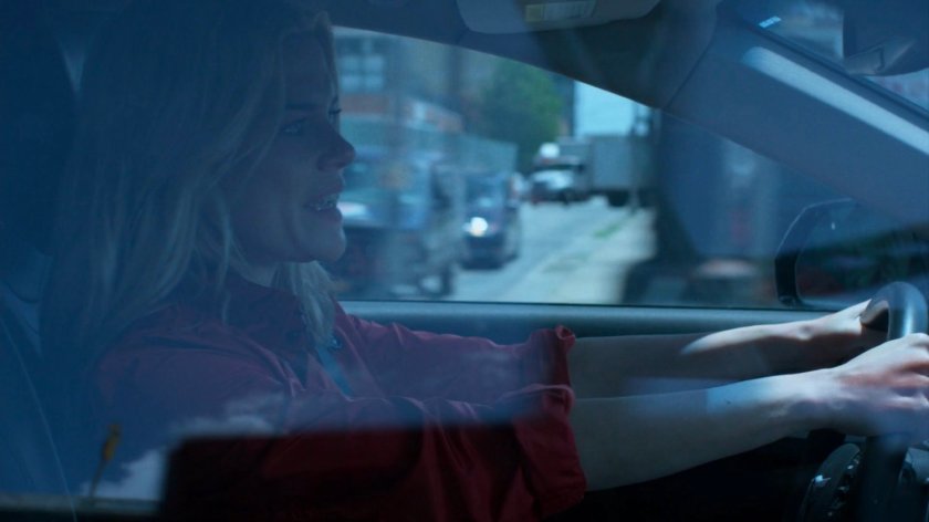 Trish, in her car, speeding through city streets.