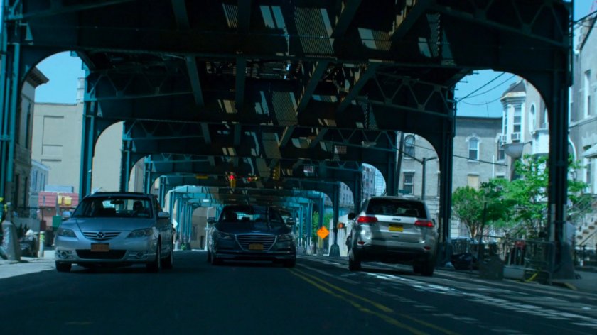 Trish's car speeding through city streets under overpass.