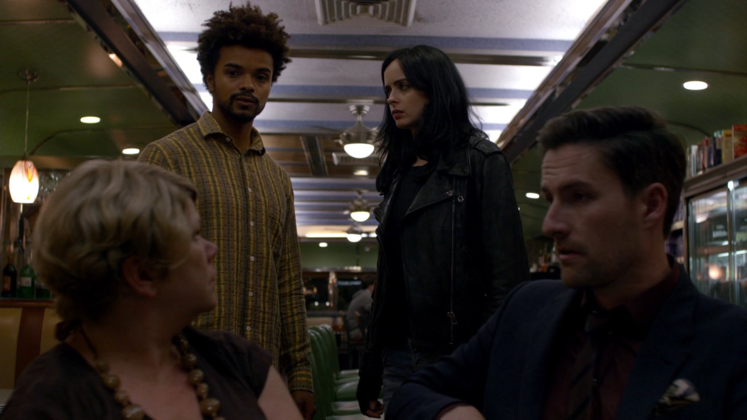 Malcolm and Jessica with members of Kilgrave's Anonymous inside Court Square Diner at night.