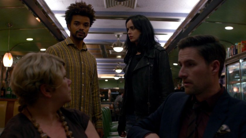 Malcolm and Jessica with members of Kilgrave's Anonymous inside Court Square Diner at night.