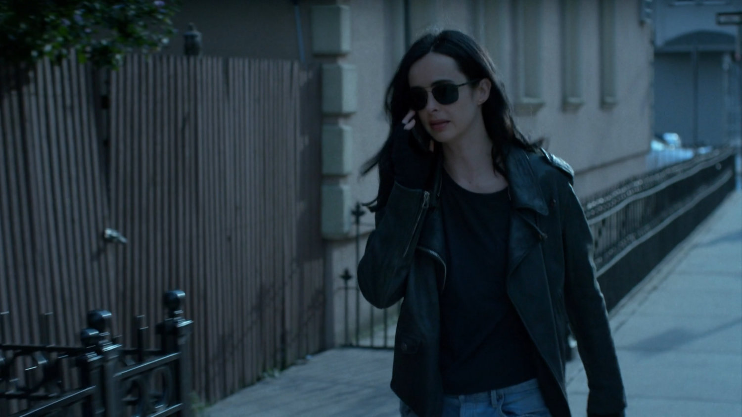 Jessica walking on the sidewalk talking on phone.