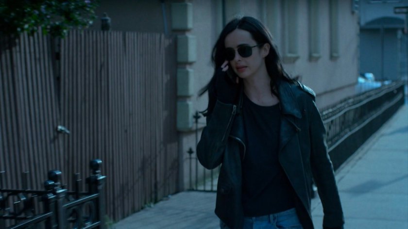 Jessica walking on the sidewalk talking on phone.