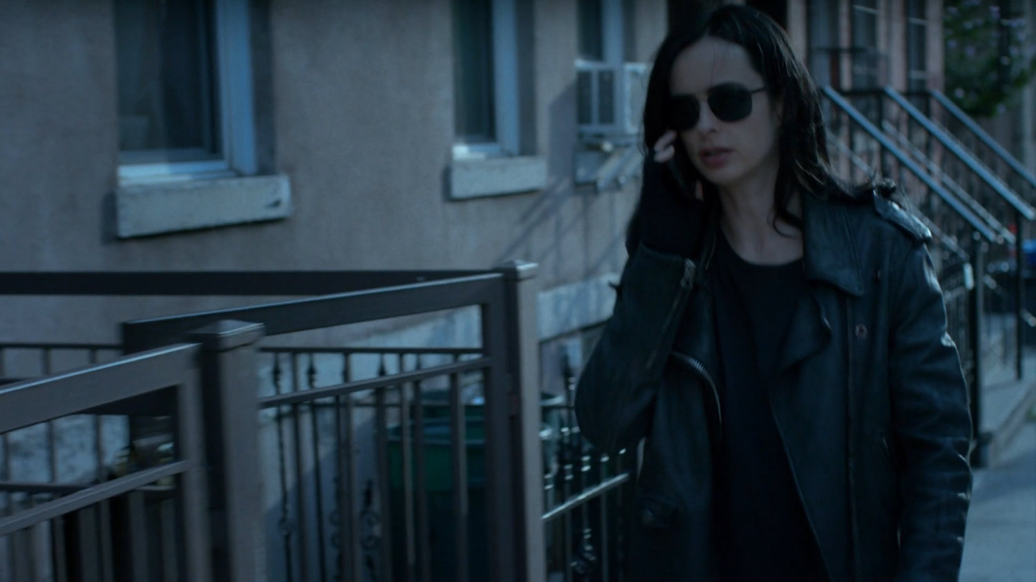 Jessica walking on the sidewalk talking on phone.